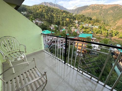 Balcony with cane chair looking over a hillside of painted houses and forested ridges